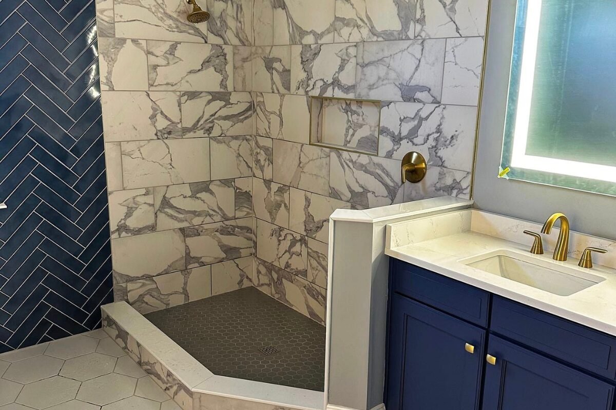 Elegant tub-to-shower conversion in Rock Hill, SC, featuring white and gray tiles with stylish gold faucets.