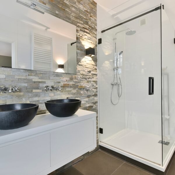 Chic bathroom remodel in Rock Hill featuring a glass shower and a striking stone wall.