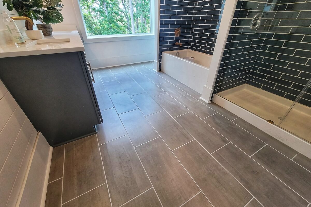 Rock Hill bathroom renovation showcasing gray tile flooring and chic blue subway tile in the shower and bathtub area.